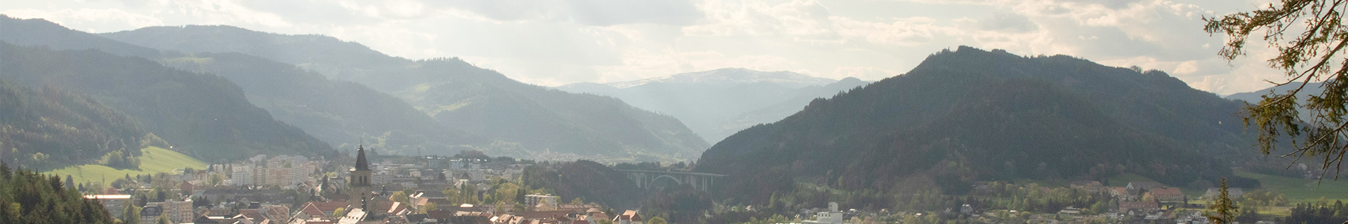 Steirische Berglandschaft mit Stadt im Tal – 24 Stunden Pflege in der Steiermark